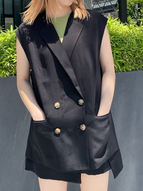 ブラック系のベスト、ブラック系のスラックス、グリーン系のタンクトップを着用したレディースの夏コーディネートの6枚目の写真