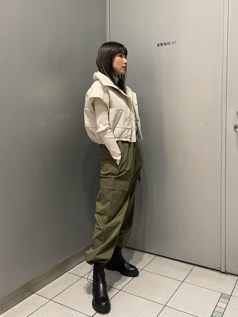 ホワイト系のダウンベスト、ブラック系のブーツ、ホワイト系のニット/セーターを着用したレディースの秋コーディネートの2枚目の写真