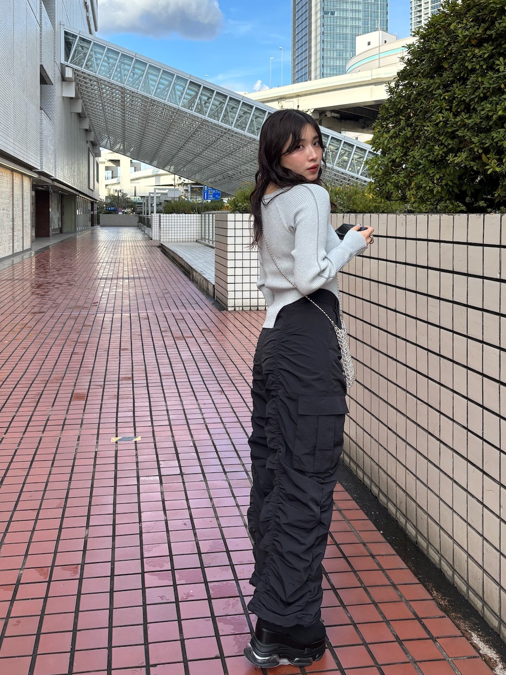 シルバー系のショルダーバッグ、ブラック系のデニムパンツ、グレー系のニット/セーターを着用したレディースの春コーディネートの3枚目の写真