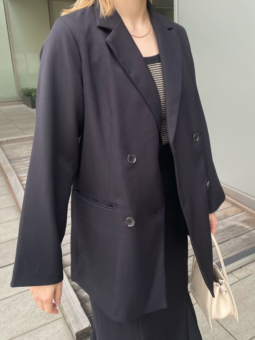 ブラック系のテーラードジャケット、ホワイト系のハンドバッグ、ブラック系のスカートを着用したレディースの春コーディネートの5枚目の写真