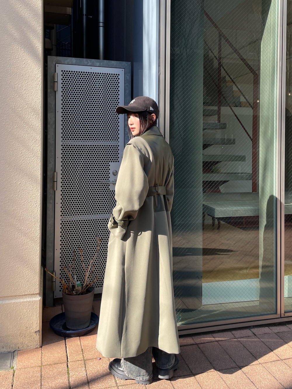 グリーン系のトレンチコートを着用したレディースの冬コーディネートの2枚目の写真