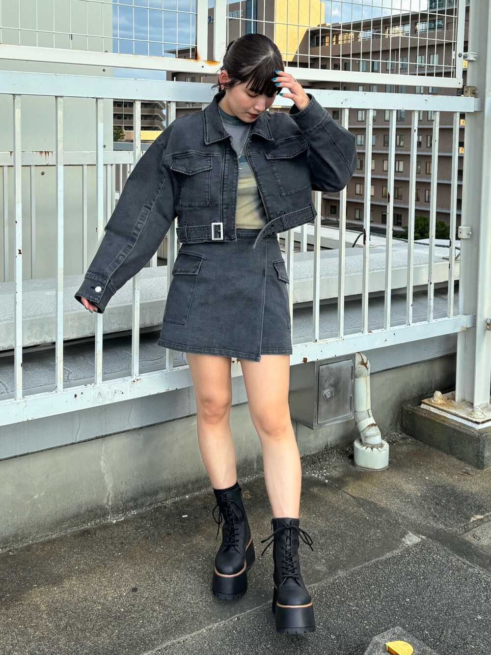 ブラック系のデニムジャケット、ブラック系のスカート、ブラック系のブーツを着用したレディースの夏コーディネートの2枚目の写真