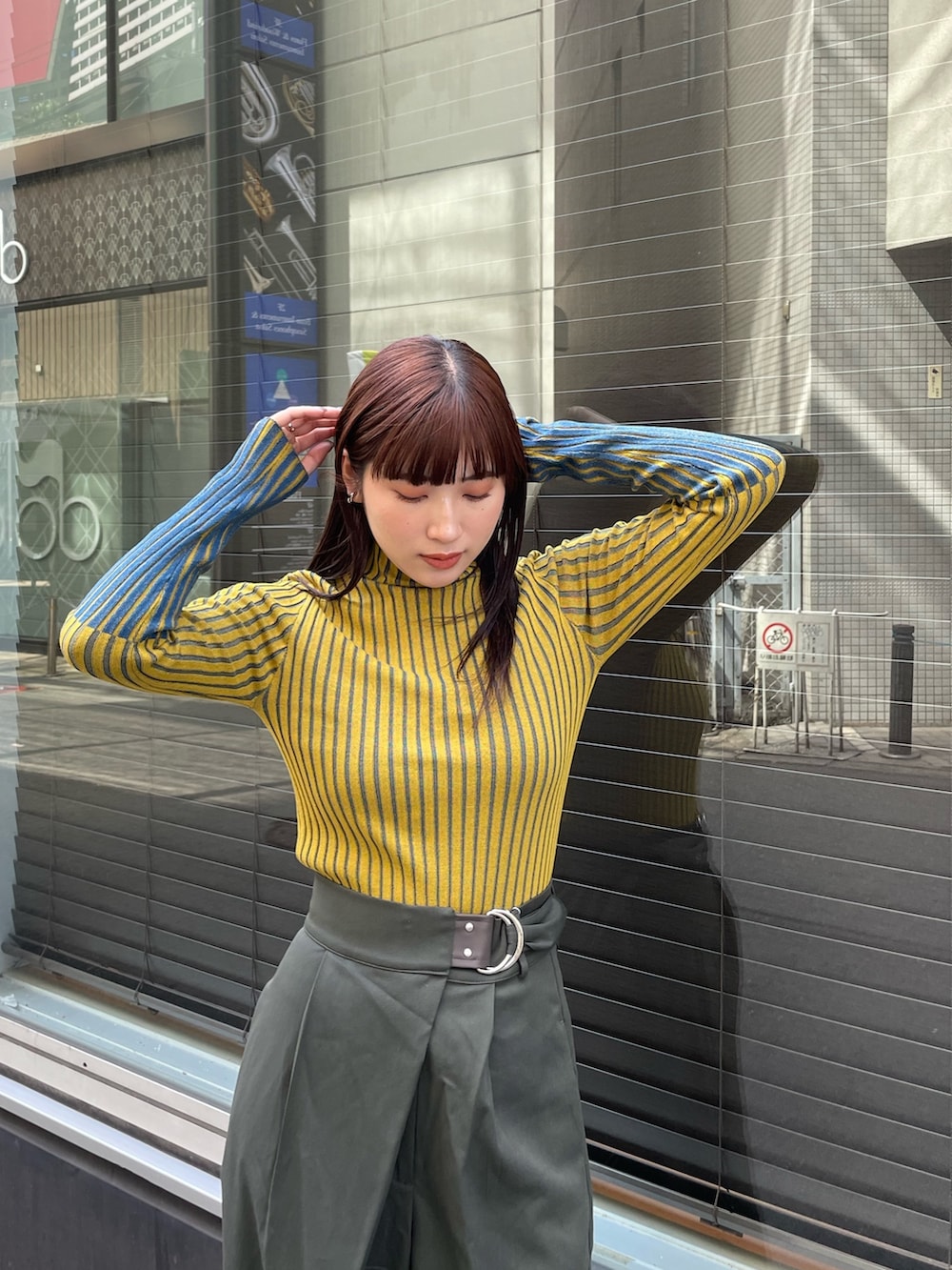 イエロー系のニット/セーター、ベージュ系のスラックスを着用したレディースの夏コーディネートの4枚目の写真