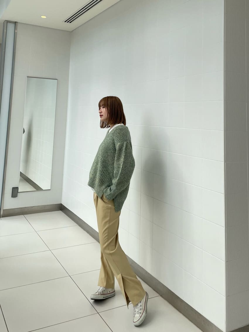 グリーン系のニット/セーター、イエロー系のスラックスを着用したレディースの冬コーディネートの2枚目の写真