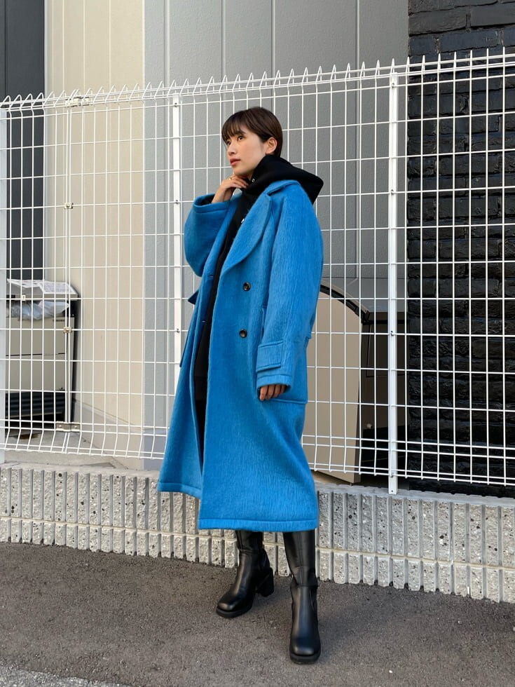 ブラック系のブーツ、ブラック系のパーカー、ブルー系のチェスターコートを着用したレディースの秋コーディネートの2枚目の写真