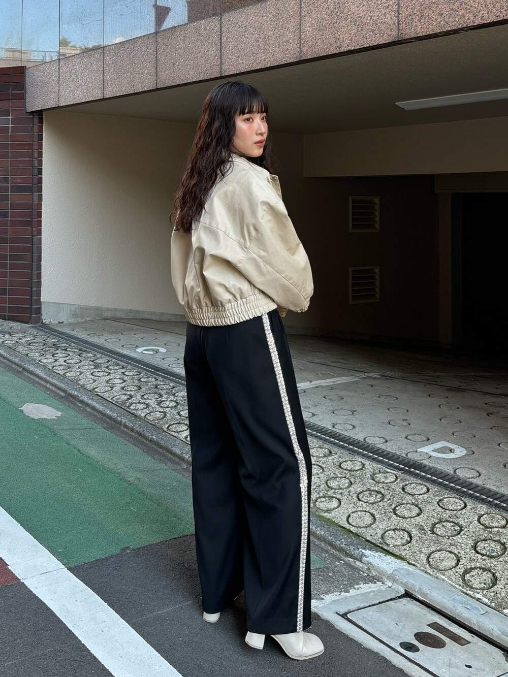 ホワイト系のブルゾン、ブラック系のその他パンツを着用したレディースの秋コーディネートの2枚目の写真