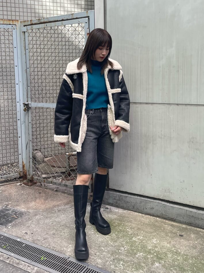 ブラック系のブーツ、ブルー系のニット/セーター、ブラック系のムートンコートを着用したレディースの秋コーディネートの2枚目の写真