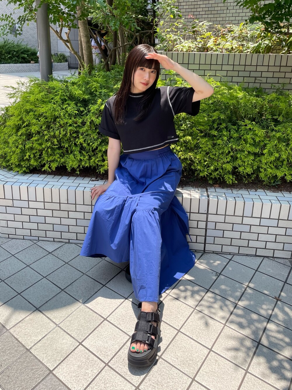 ブラック系のTシャツ/カットソー、ブルー系のスカート、ブラック系のサンダルを着用したレディースの夏コーディネートの3枚目の写真