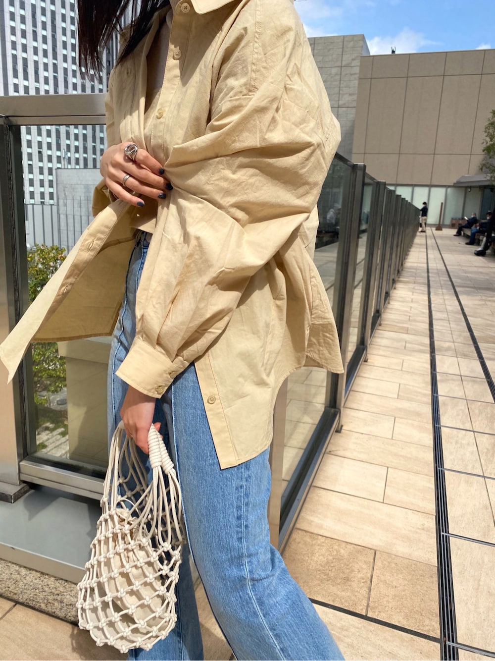 ホワイト系のニット/セーター、イエロー系のシャツ/ブラウス、ホワイト系のハンドバッグを着用したレディースの春コーディネートの3枚目の写真