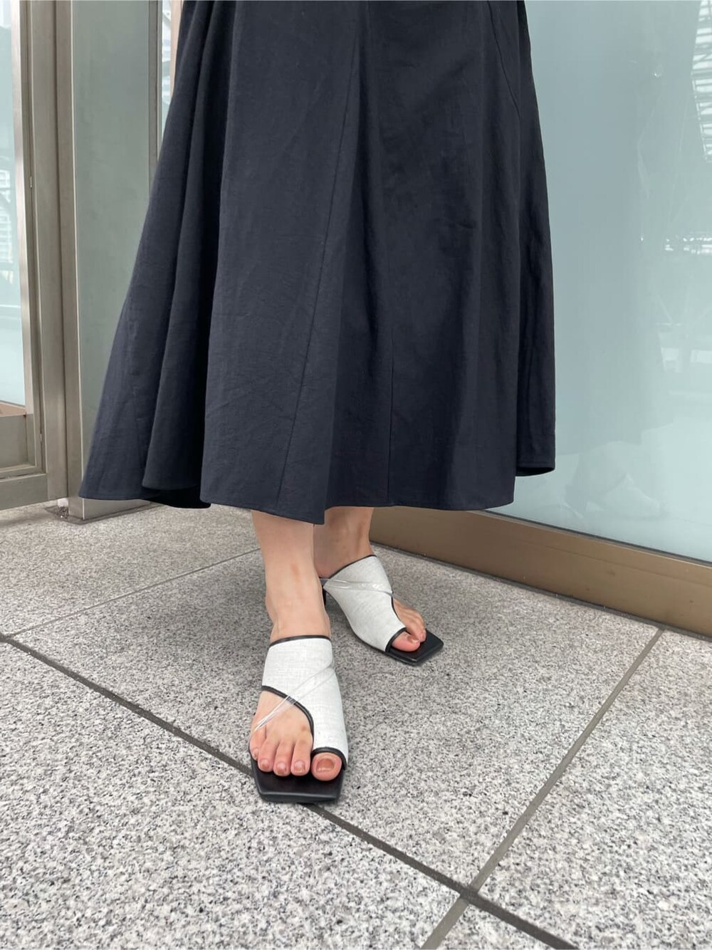 ブラック系のサンダル、ブラック系のスカート、ブラック系のTシャツ/カットソーを着用したレディースの夏コーディネートの7枚目の写真