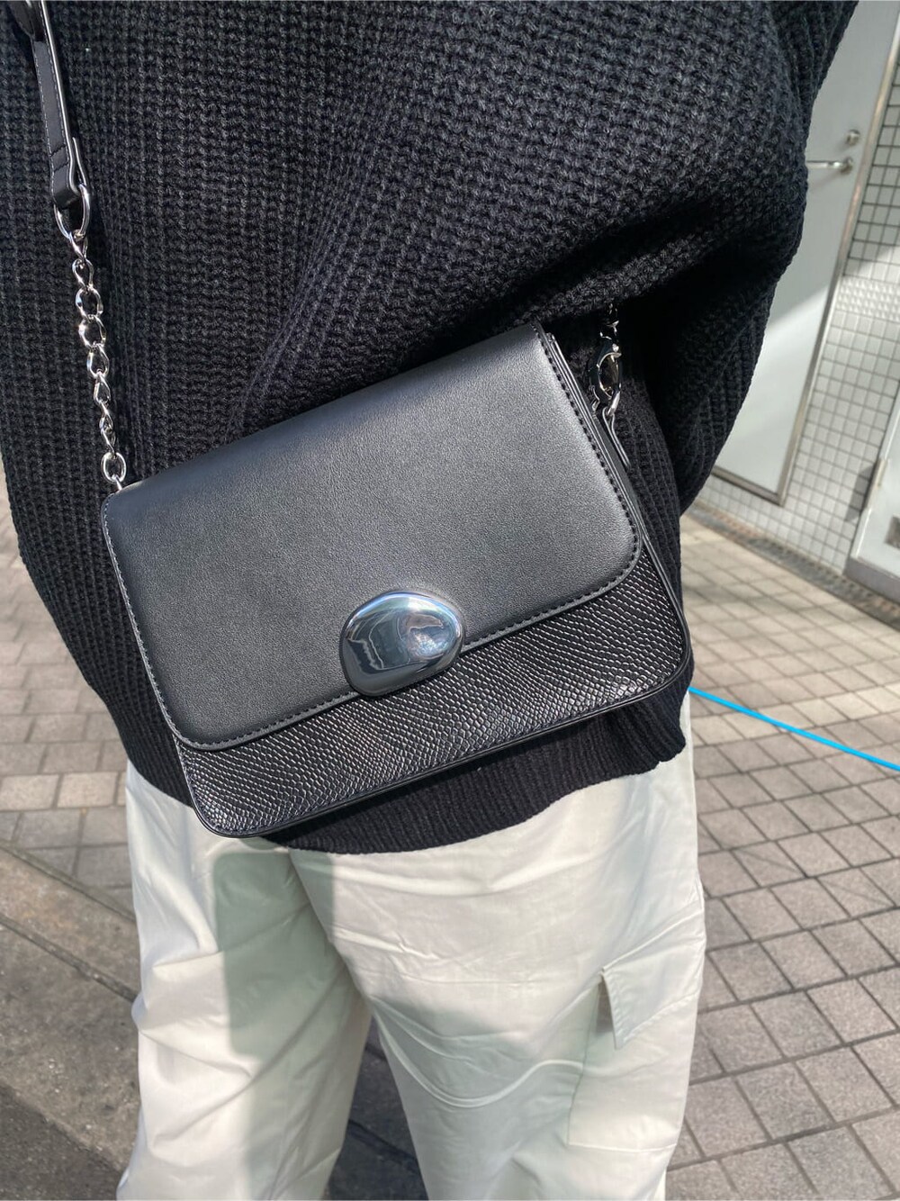 ブラック系のブーツ、ブラック系のニット/セーター、ブラック系のショルダーバッグを着用したレディースの秋コーディネートの6枚目の写真