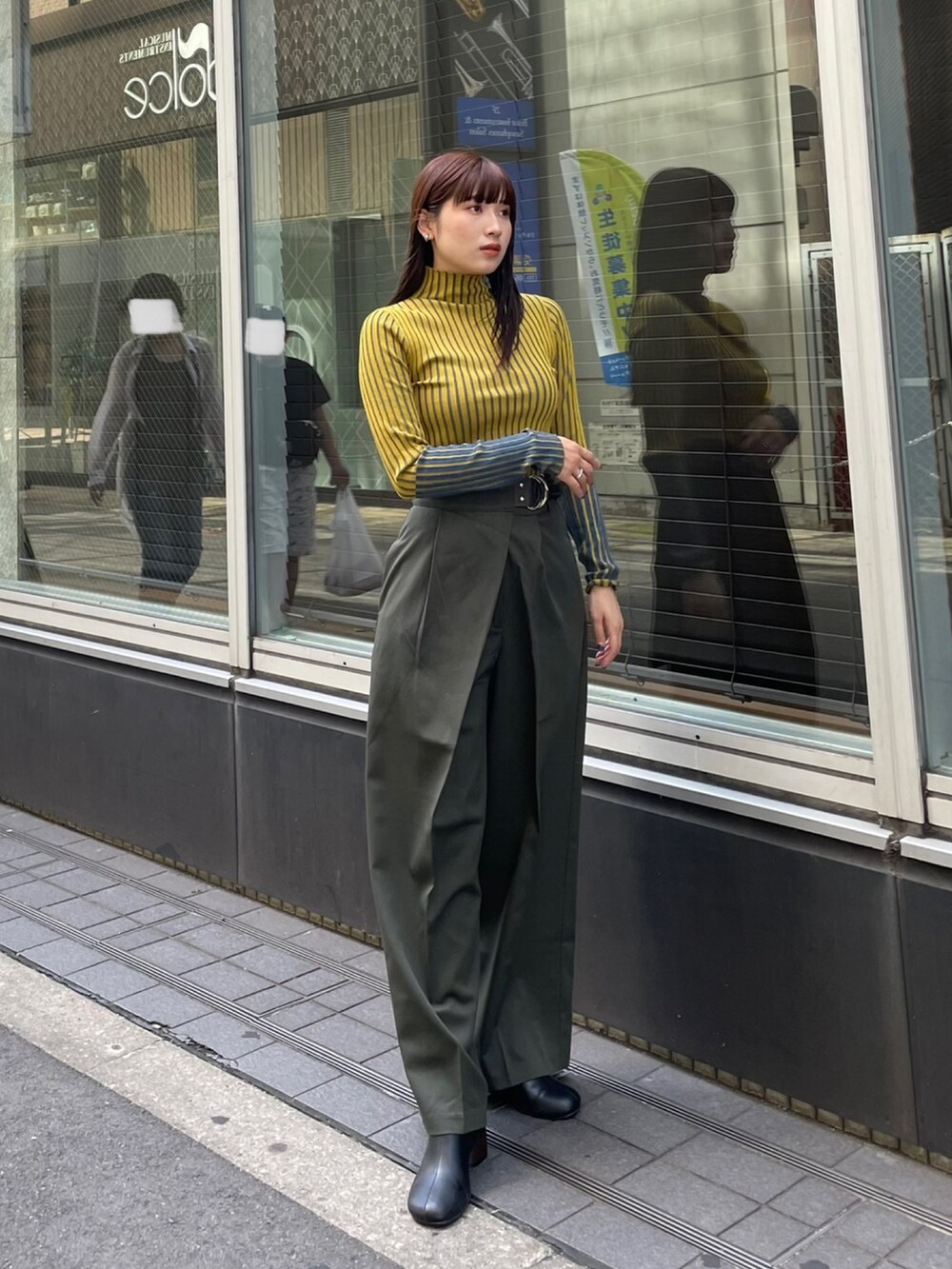 イエロー系のニット/セーター、ベージュ系のスラックスを着用したレディースの夏コーディネートの2枚目の写真