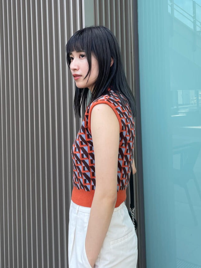 ブラック系のショルダーバッグ、オレンジ系のニット/セーターを着用したレディースの夏コーディネートの6枚目の写真