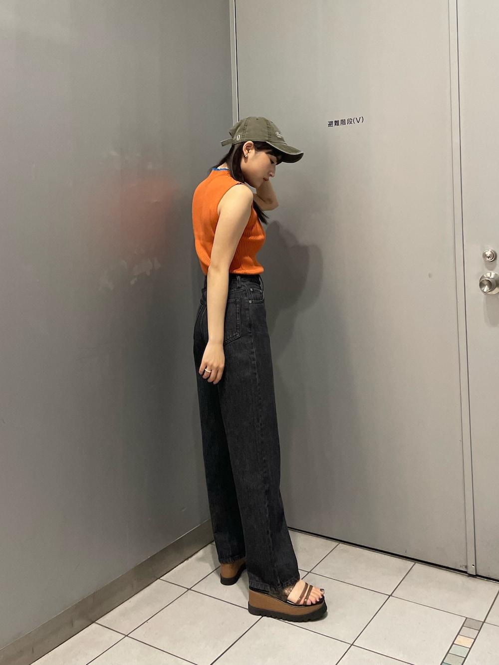 オレンジ系のニット/セーター、ブラック系のデニムパンツ、ブラック系のサンダルを着用したレディースの春コーディネートの3枚目の写真