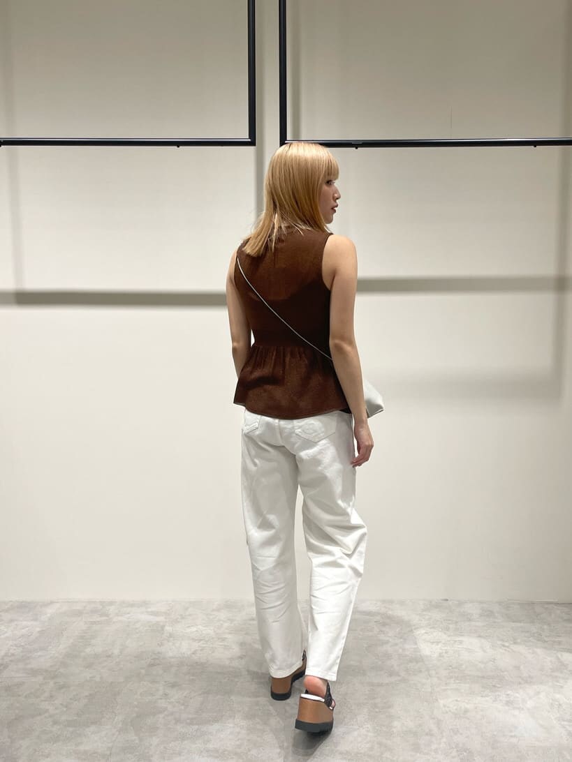 ホワイト系のデニムパンツ、ブラウン系のワンピース、ホワイト系のショルダーバッグを着用したレディースの春コーディネートの3枚目の写真