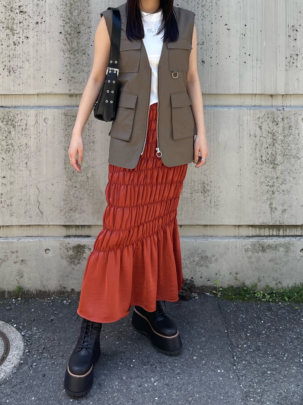 ホワイト系のTシャツ/カットソー、オレンジ系のスカート、ベージュ系のベストを着用したレディースの夏コーディネートの2枚目の写真