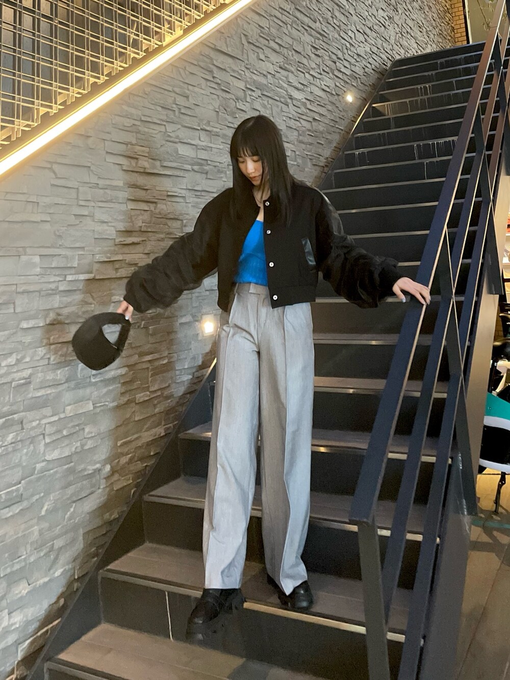 ブラック系のブルゾン、グレー系のスラックス、ブルー系のニット/セーターを着用したレディースの春コーディネートの3枚目の写真