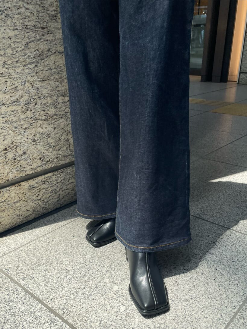 グリーン系のハンドバッグ、ブラック系のブーツ、ブラック系のTシャツ/カットソーを着用したレディースの夏コーディネートの8枚目の写真