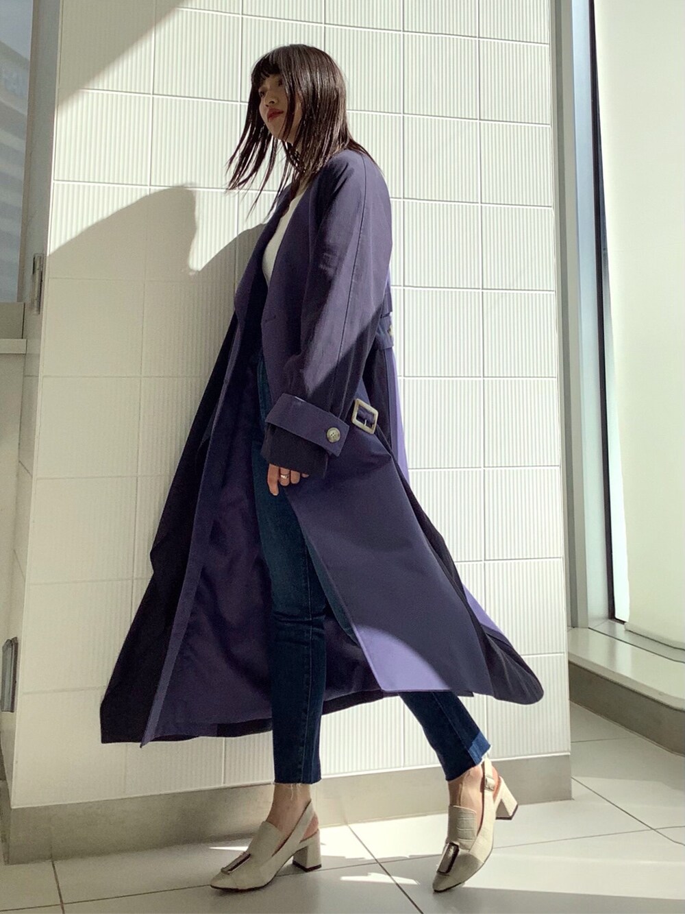 ブルー系のデニムパンツ、ブルー系のトレンチコート、ホワイト系のパンプスを着用したレディースの冬コーディネートの2枚目の写真