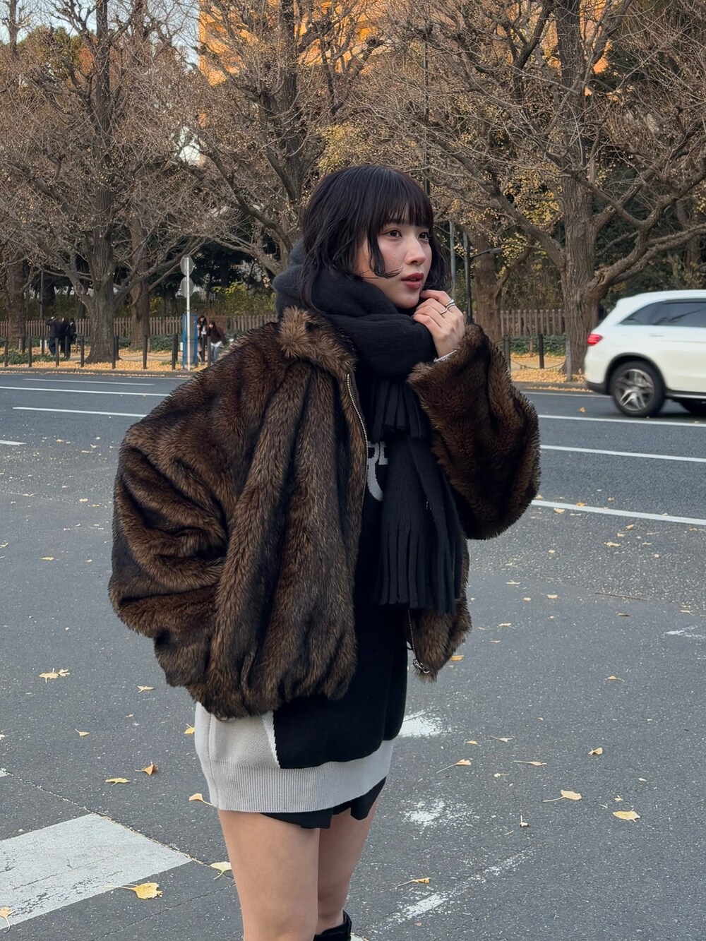 ブラウン系のブルゾン、ブラック系のワンピース、ブラック系のブーツを着用したレディースの冬コーディネートの2枚目の写真