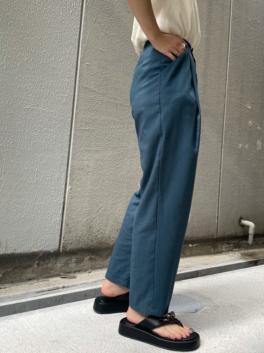 グリーン系のスラックス、ブラック系のサンダル、ホワイト系のTシャツ/カットソーを着用したレディースの夏コーディネートの6枚目の写真