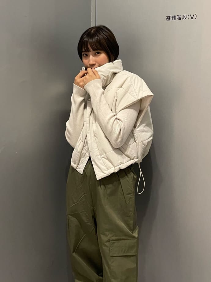 ホワイト系のダウンベスト、ブラック系のブーツ、ホワイト系のニット/セーターを着用したレディースの秋コーディネートの5枚目の写真