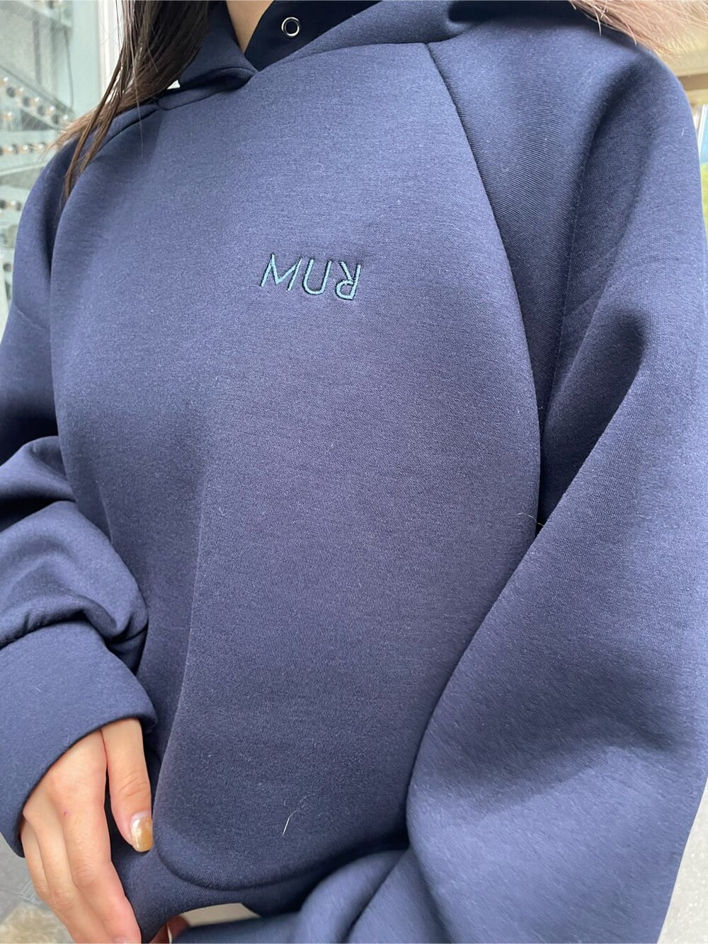 ホワイト系のスラックス、ブラック系のブーツ、ブルー系のパーカーを着用したレディースの秋コーディネートの4枚目の写真