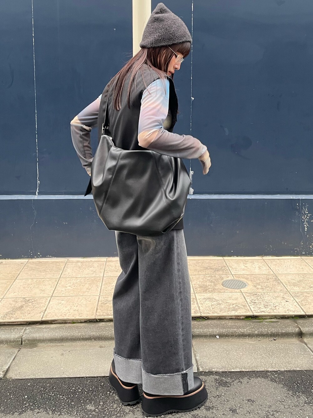 グレー系のデニムパンツ、ブラック系のハンドバッグ、ブラック系のベストを着用したレディースの夏コーディネートの3枚目の写真