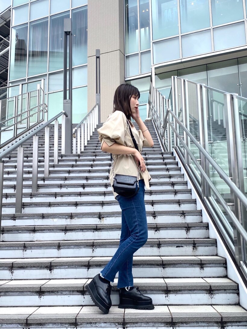 ベージュ系のシャツ/ブラウス、ブルー系のデニムパンツ、ブラック系のハンドバッグを着用したレディースの春コーディネートの4枚目の写真