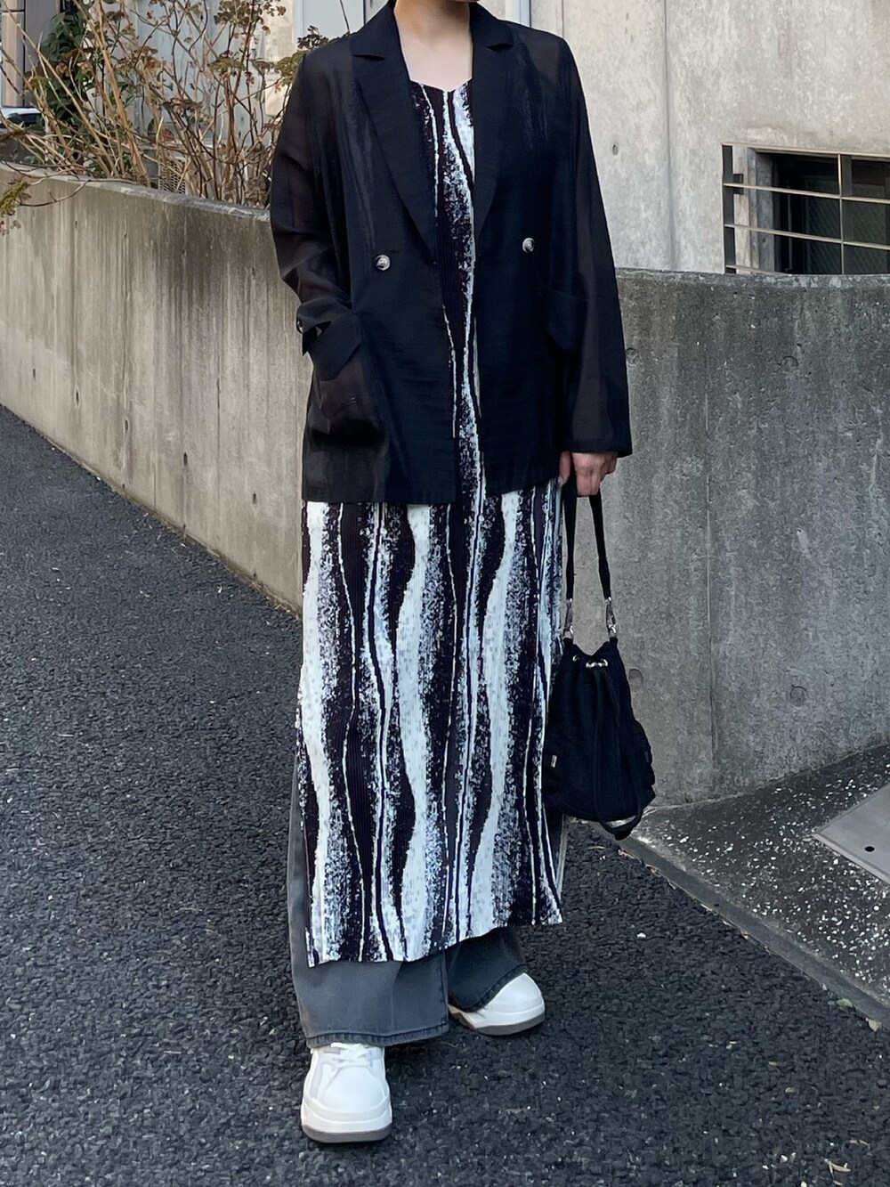 ブラック系のテーラードジャケット、ブラック系のワンピース、ブラック系のデニムパンツを着用したレディースの春コーディネートの4枚目の写真