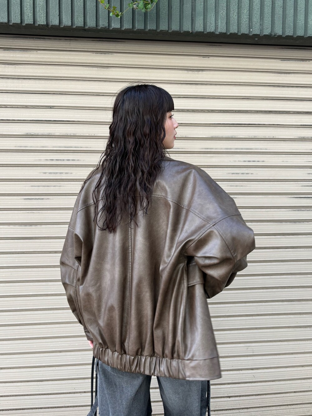 ブラウン系のブルゾン、ブラック系のデニムパンツ、ホワイト系のニット/セーターを着用したレディースの秋コーディネートの5枚目の写真