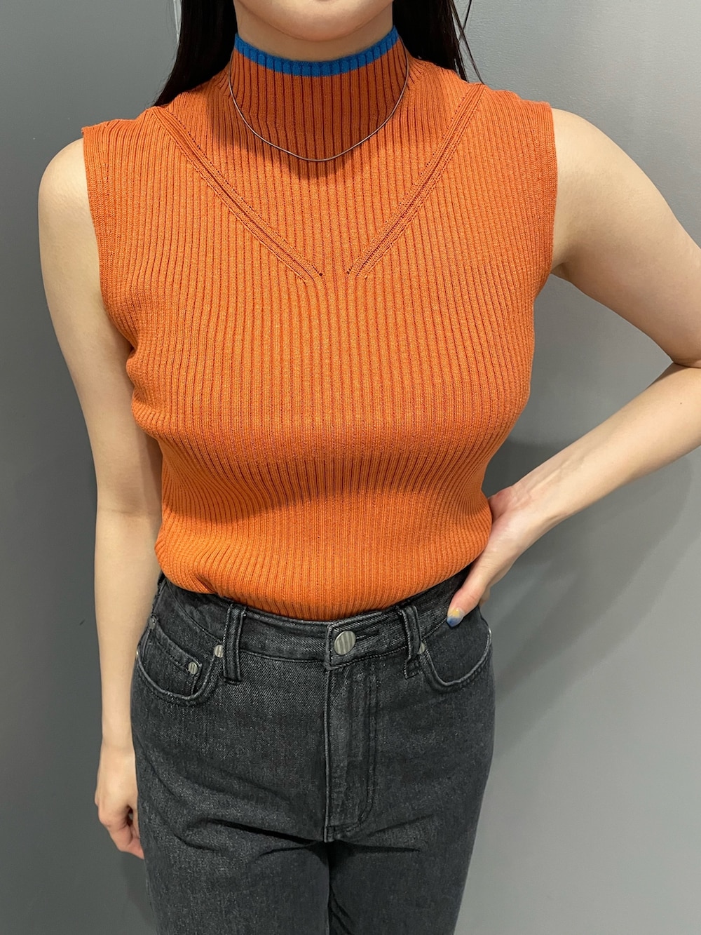 オレンジ系のニット/セーター、ブラック系のデニムパンツ、ブラック系のサンダルを着用したレディースの春コーディネートの5枚目の写真