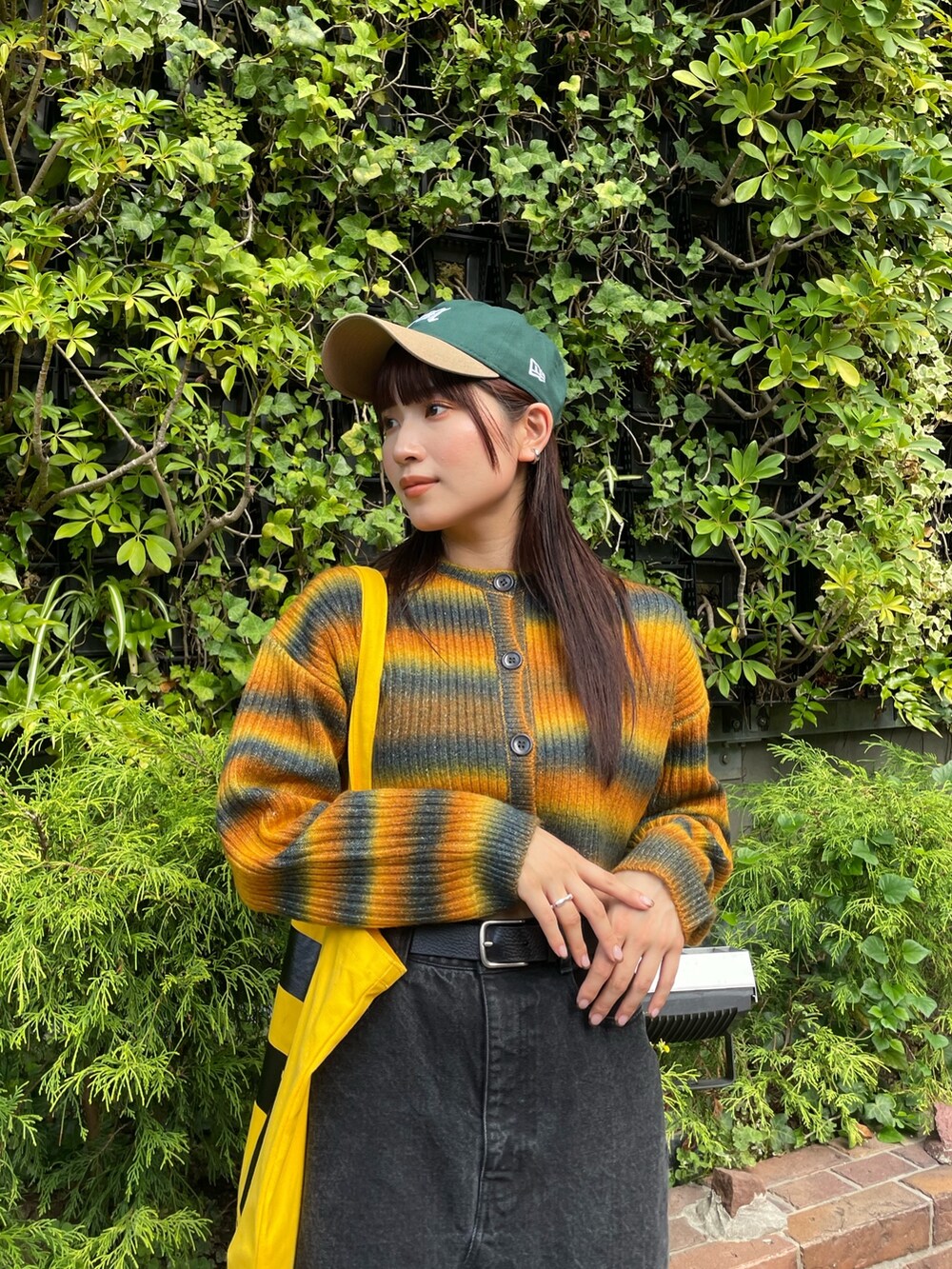 イエロー系のカーディガン/ボレロ、グリーン系のキャップを着用したレディースの秋コーディネートの2枚目の写真