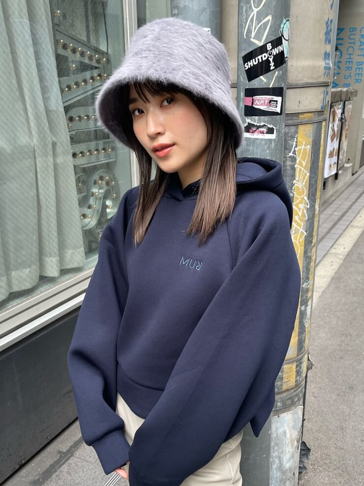 ホワイト系のスラックス、ブラック系のブーツ、ブルー系のパーカーを着用したレディースの秋コーディネートの3枚目の写真