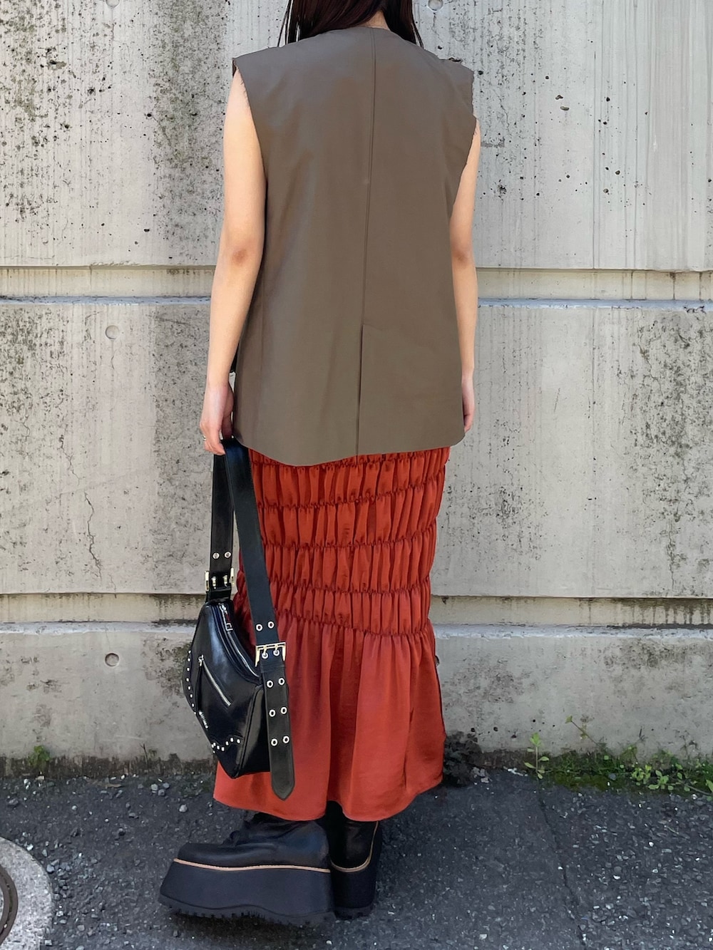 ホワイト系のTシャツ/カットソー、オレンジ系のスカート、ベージュ系のベストを着用したレディースの夏コーディネートの3枚目の写真