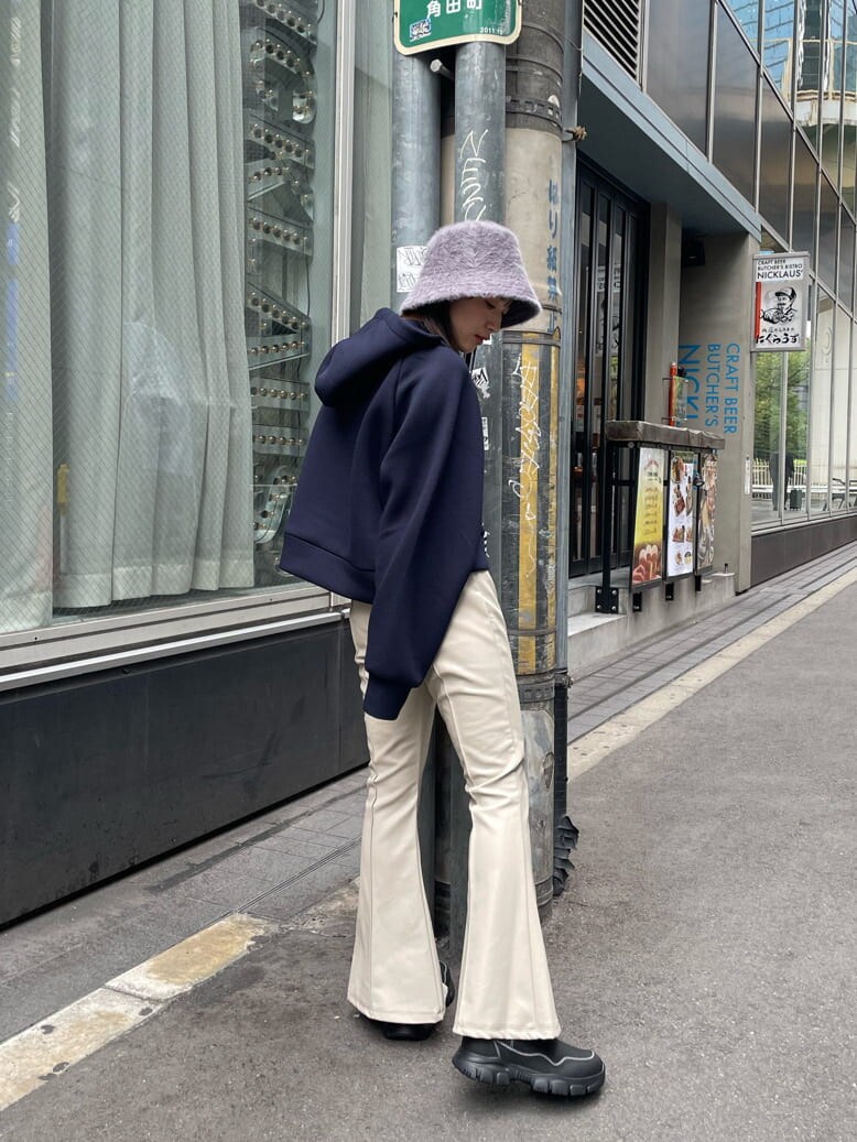 ホワイト系のスラックス、ブラック系のブーツ、ブルー系のパーカーを着用したレディースの秋コーディネートの2枚目の写真