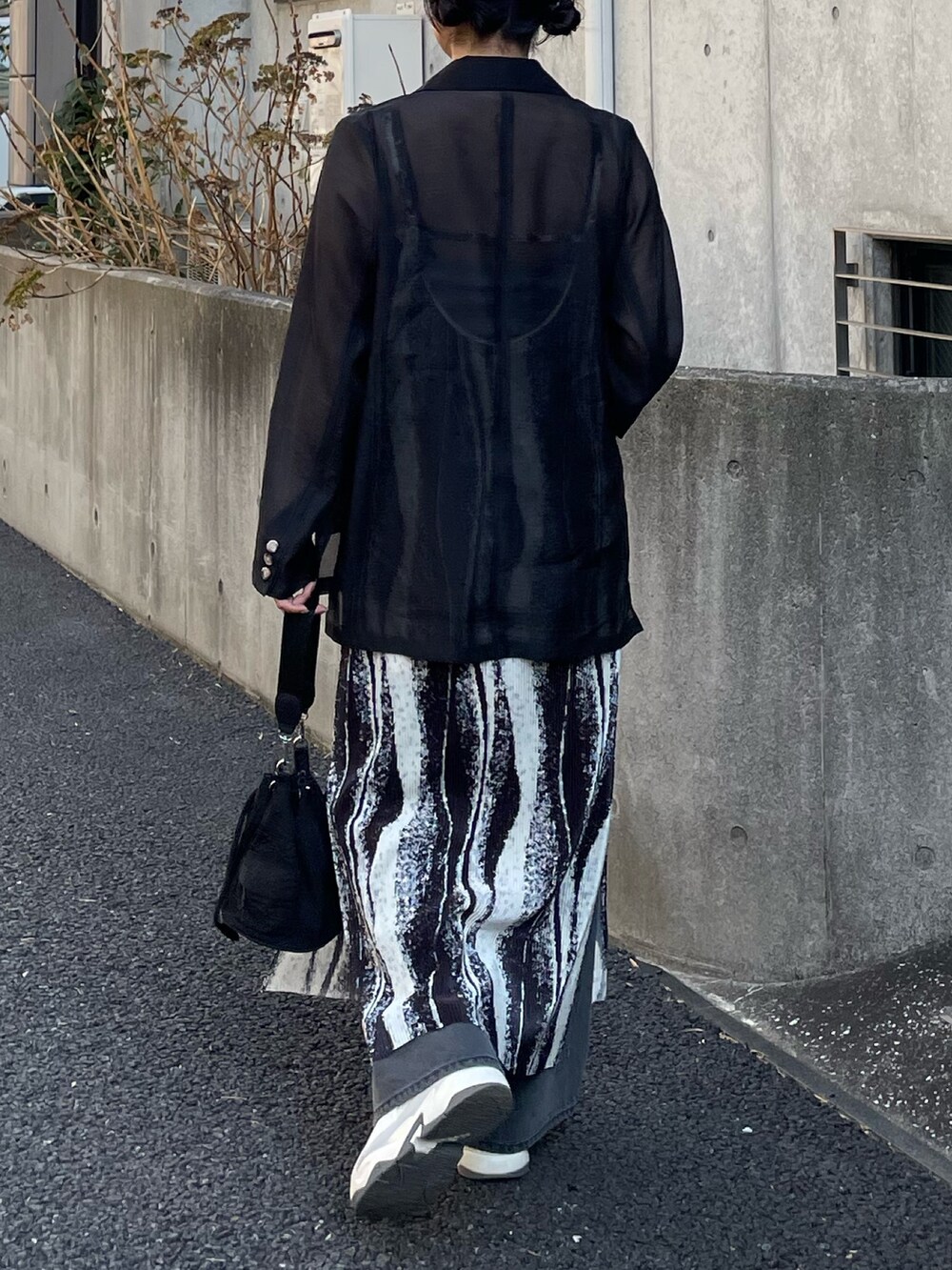 ブラック系のテーラードジャケット、ブラック系のワンピース、ブラック系のデニムパンツを着用したレディースの春コーディネートの3枚目の写真