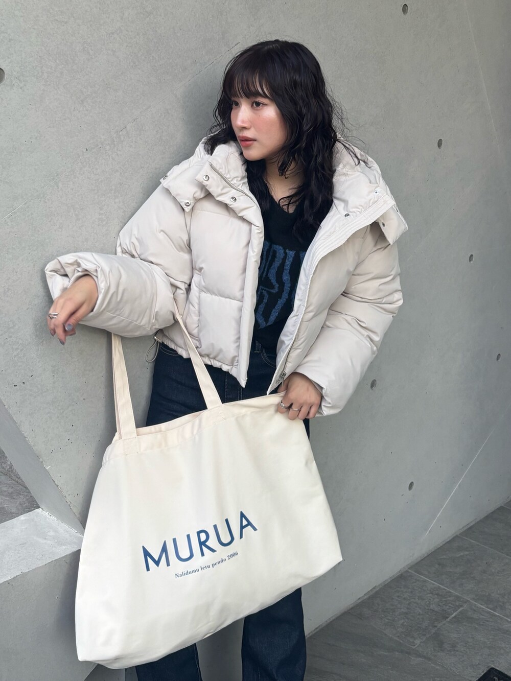 ホワイト系のブルゾン、ブラック系のニット/セーター、ブルー系のデニムパンツを着用したレディースの冬コーディネートの4枚目の写真