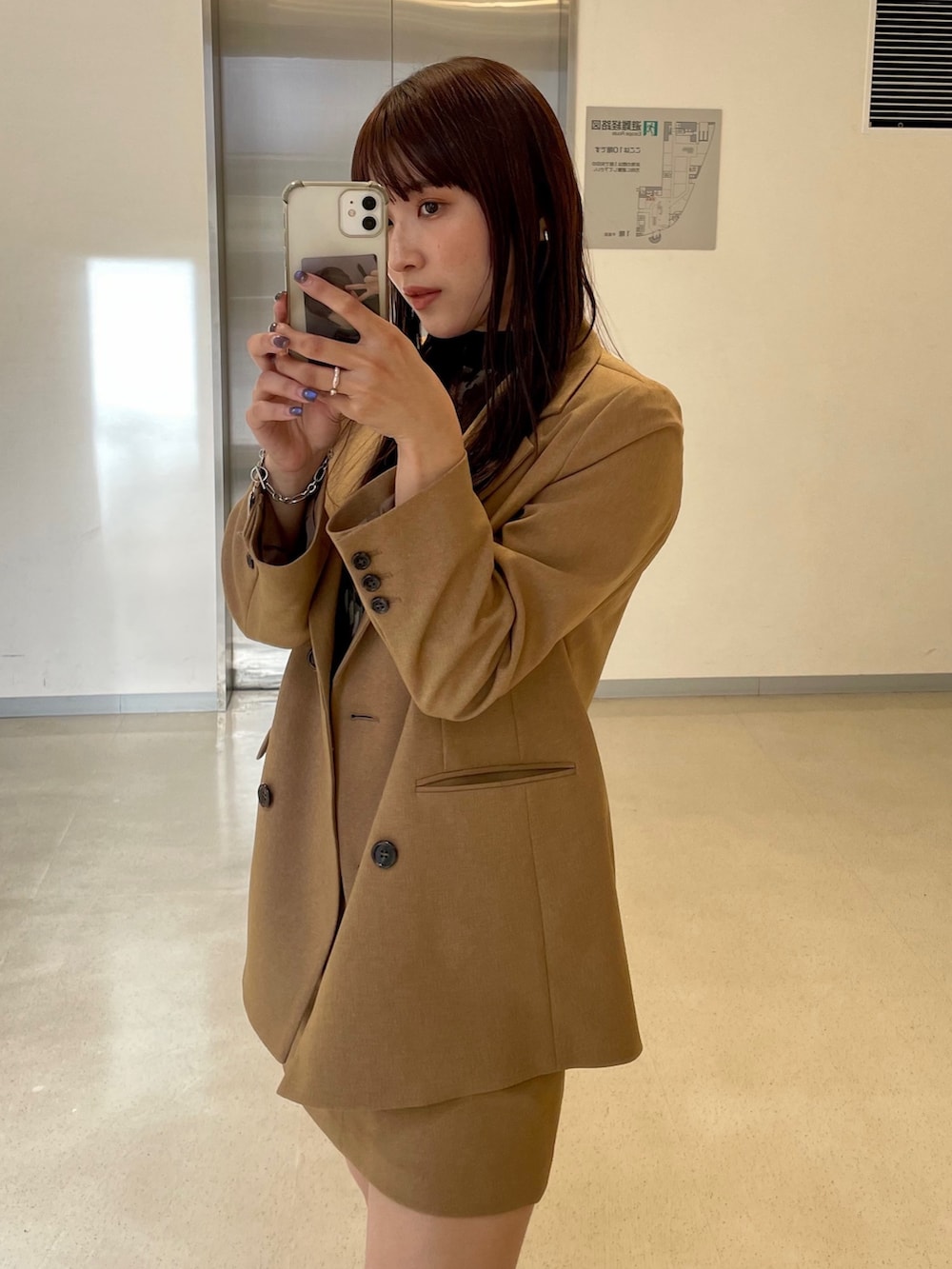 ベージュ系のスカート、グレー系のテーラードジャケットを着用したレディースの秋コーディネートの3枚目の写真