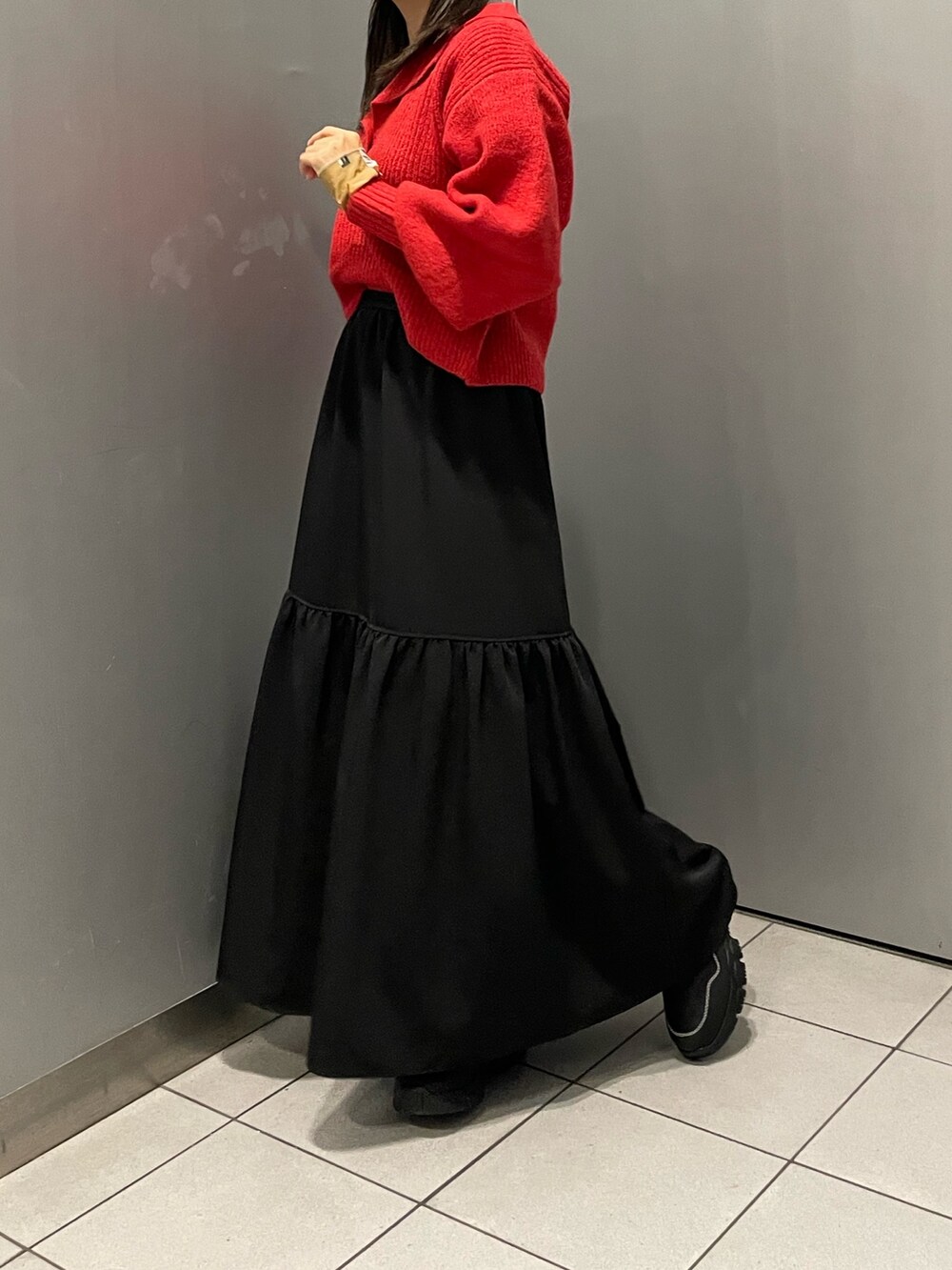 レッド系のニット/セーター、ブラック系のスカート、ブラック系のブーツを着用したレディースの秋コーディネートの5枚目の写真