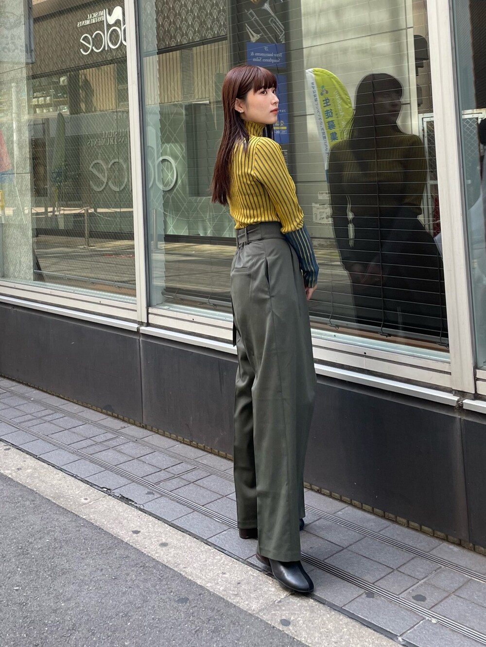 イエロー系のニット/セーター、ベージュ系のスラックスを着用したレディースの夏コーディネートの3枚目の写真