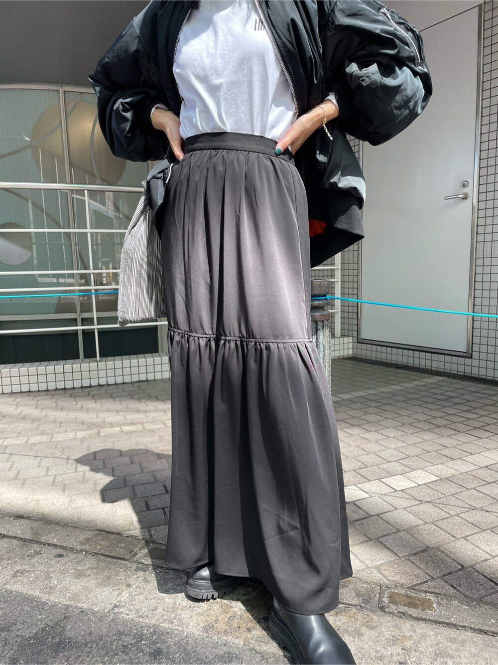 ブラック系のスカート、ブラック系のブルゾン、オレンジ系のハットを着用したレディースの秋コーディネートの6枚目の写真