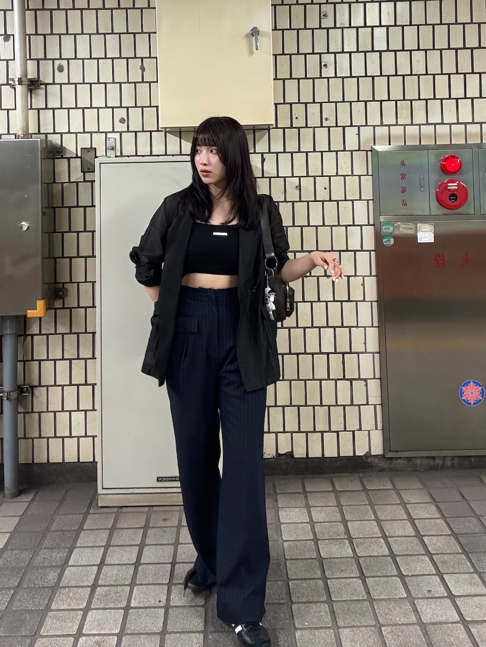 ブラック系のテーラードジャケット、ブルー系のその他パンツ、ブラウン系のハンドバッグを着用したレディースの夏コーディネートの2枚目の写真