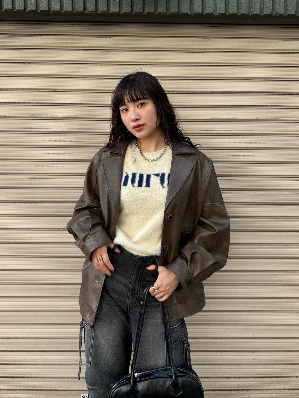 ブラウン系のブルゾン、ブラック系のデニムパンツ、ホワイト系のニット/セーターを着用したレディースの秋コーディネートの4枚目の写真