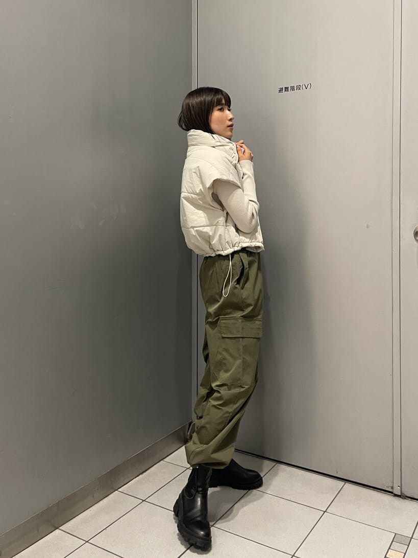 ホワイト系のダウンベスト、ブラック系のブーツ、ホワイト系のニット/セーターを着用したレディースの秋コーディネートの3枚目の写真