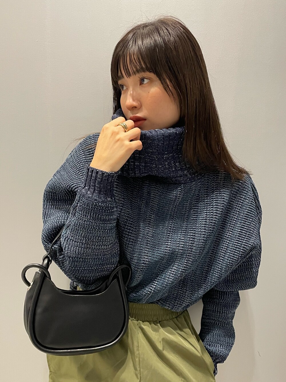 ブルー系のニット/セーター、ブラック系のハンドバッグ、ブラック系のブーツを着用したレディースの秋コーディネートの5枚目の写真