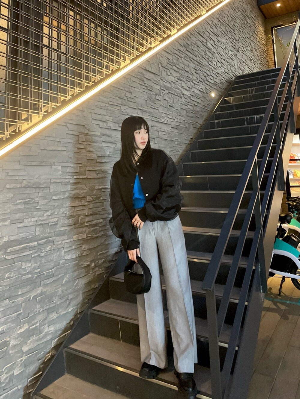 ブラック系のブルゾン、グレー系のスラックス、ブルー系のニット/セーターを着用したレディースの春コーディネートの2枚目の写真