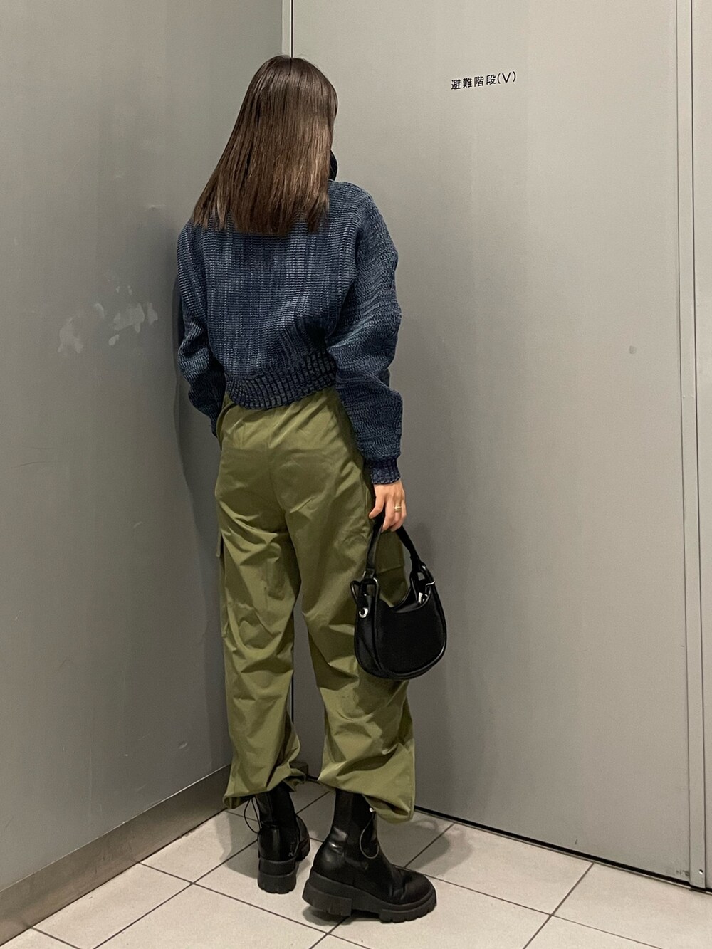 ブルー系のニット/セーター、ブラック系のハンドバッグ、ブラック系のブーツを着用したレディースの秋コーディネートの3枚目の写真