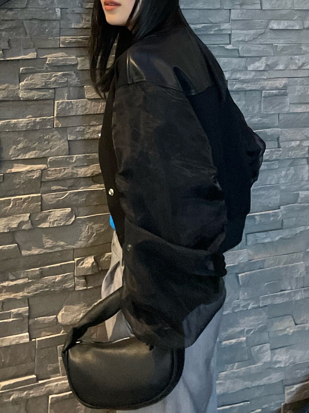 ブラック系のブルゾン、グレー系のスラックス、ブルー系のニット/セーターを着用したレディースの春コーディネートの4枚目の写真