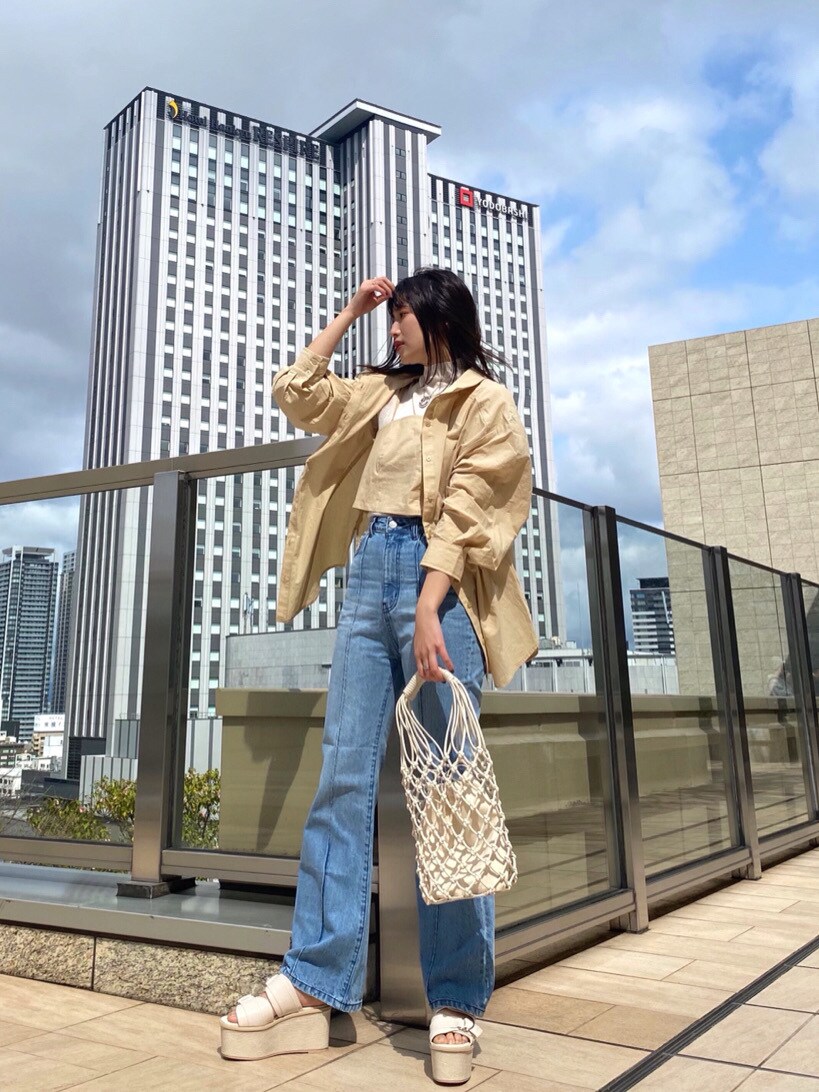 ホワイト系のニット/セーター、イエロー系のシャツ/ブラウス、ホワイト系のハンドバッグを着用したレディースの春コーディネートの4枚目の写真